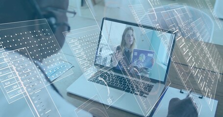 Watching senior man analyzing charts on online call at office desk, with headset laptop clipboard