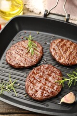 Pan with grilled patties and spices on table, closeup