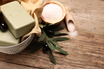 Natural soap bars, olives and sea salt on wooden table, above view. Space for text