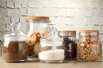 Glass jars with different products on wooden table