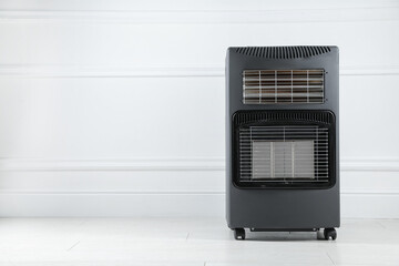 Obraz premium Electric heater on floor near light wall indoors. Space for text