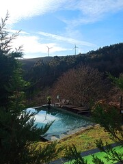 Solo travel, sustainable travel, wellness travel. Infinity pool at a remote hotel in Portugal during autumn.Clear blue water reflection, distant wind turbines on green hills. nature stock photos