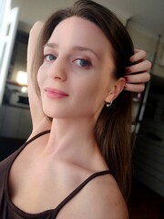 Close up portrait of a young attractive woman holding a smartphone and taking a selfie. Beautiful woman looking at camera and smiling. Pretty female with long hair, blonde takes selfie on mobile phone