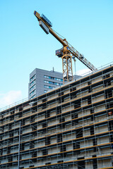 Construction crane and building under construction against blue sky