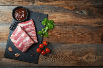 Raw pork ribs with spices, salt and rosemary on dark wooden background
