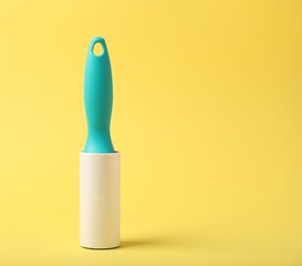 One lint roller on yellow background, space for text