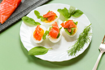 Whites and yolks of eggs with salmon for cold serving on a green background