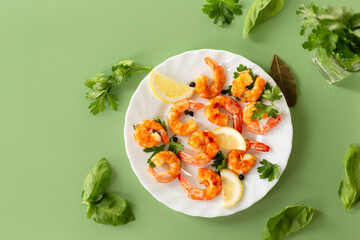 Juicy fried shrimps with lemon slices in a plate isolated on green