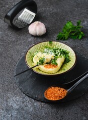 Preparing salted butter with garlic and parsley in a ceramic bowl against a dark concrete background.
