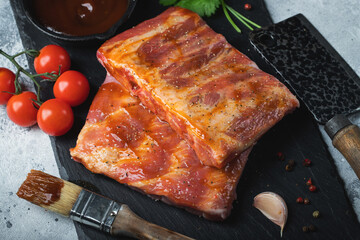Ready for BBQ raw pork spare ribs with barbecue sauce. Black background. Top view