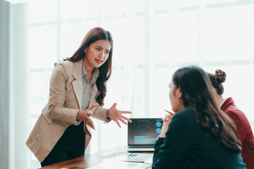 Asian businesswomen arguing during a meeting, expressing frustration over financial charts displayed on a laptop at the corporate office