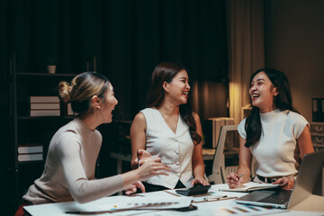 Group of asian businesswomen laughing and working together during a late night meeting in the office