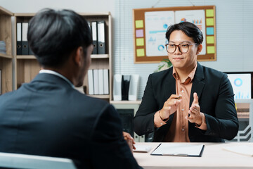 Two businessmen sitting at a desk, engaging in a job interview within a modern office environment, discussing career opportunities and qualifications