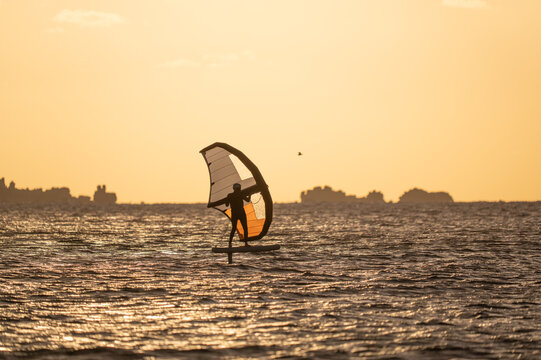 Wingfoiling in Brittany at sunset, a few rocks in the background