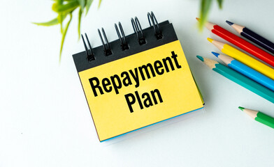 Repayment Plan text on notepad with colored pencils on office desk