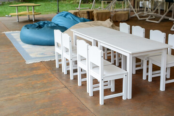 children's playroom on the terrace. white wooden tables and chairs for children.