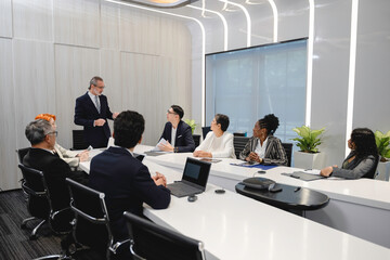 Diverse business professionals having a corporate meeting in a modern conference room, discussing strategy and sharing ideas with digital devices and teamwork collaboration.
