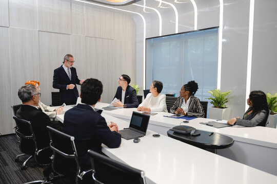 Diverse business professionals having a corporate meeting in a modern conference room, discussing strategy and sharing ideas with digital devices and teamwork collaboration. - Powered by Adobe