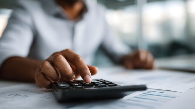 Close up of hands using a calculator for financial analysis on a desk with documents