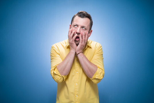 Bored guy feeling sleepy and reluctant stare apathy, boring concept over blue background, dresses in yellow shirt