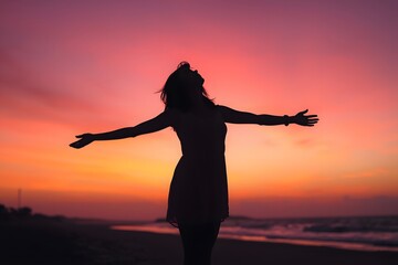 Woman Silhouetted Against a Vibrant Sunset Sky with Arms Raised