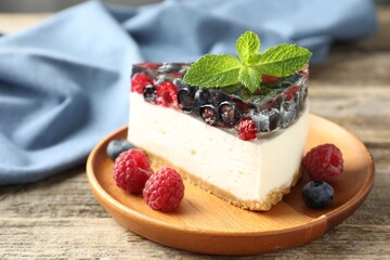 Piece of delicious cheesecake with berries and mint on wooden table, closeup