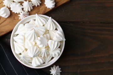Delicious meringue cookies in bowl on wooden table, top view. Space for text