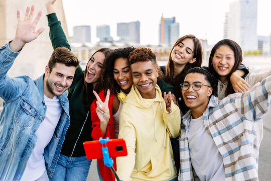 Multi-ethnic group of young students taking a selfie with a selfie stick, smiling and having fun together outdoors