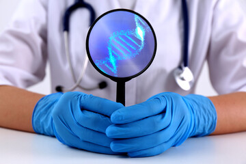 Scientist holding magnifying glass with DNA spiral inside at table, closeup. Genetic analysis and...