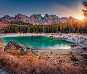 Amazing autumn sunrise on shallow Karersee lake, Province of Bolzano - South Tyrol. Stunninf morning view of Dolomite Alps. Majestic outdoor scene of Itale, Europe. Beauty of nature concept background