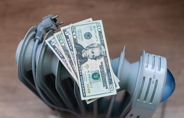An electric radiator with American dollar bills. American dollars are lying on the radiator. Expensive electricity. Energy crisis. Social problems. 