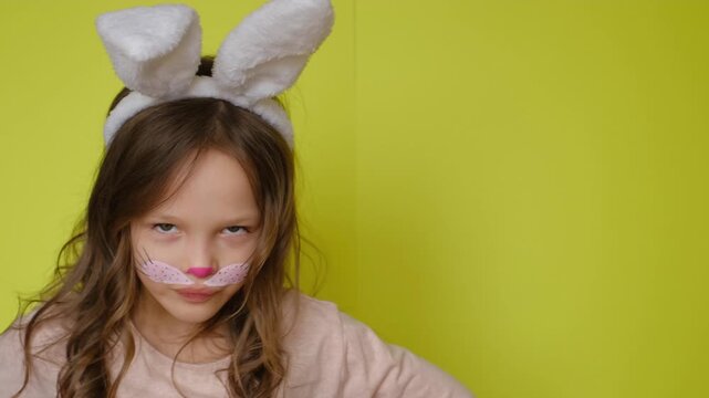 A humorous girl in a rabbit costume with a painted face makes a menacing displeased look. The feast of Holy Easter.