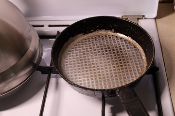 This overhead shot features an old, worn frying pan with a round piece of parchment paper resting inside it on a kitchen stove.