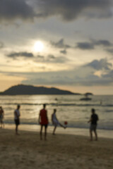 Silhouettes of young males playing soccer on beach at sunset.