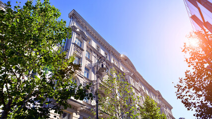 A residential building  by lush green trees and surrounded by  fresh vegetation on a clear sunny day. Modern architecture residential apartment building complex surrounded by greenery.