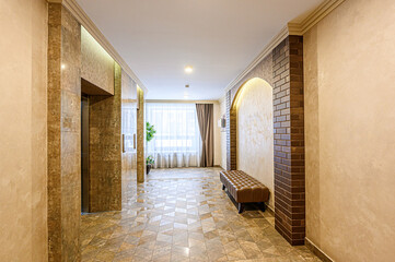 Elegant corridor with stone accents, geometric tile flooring, and a leather bench. Natural light illuminates the space