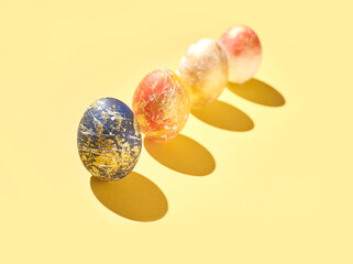 Colorful artistic easter eggs on yellow background with shadows.
