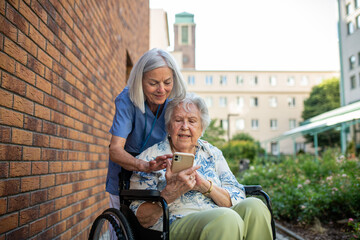 Nurse helping senior patient to find something in phone.
