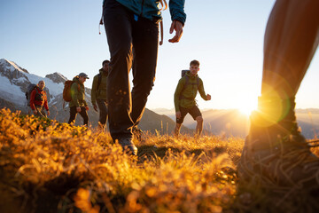 Group of hikers on a grassy mountain trail at sunset with golden backlight and alpine view. Generative AI