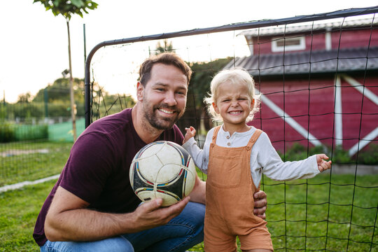 Little boy playing football with father in backyard. - Powered by Adobe