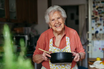 Happy senior woman cooking at home.
