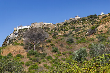 The historic Palmela Castle fortress crowns a rugged, dry hillside, demonstrating its strategic position overlooking the surrounding Portuguese landscape.