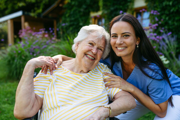 Fototapeta na wymiar Portrait of caregiver taking care of elderly woman in wheelchair.