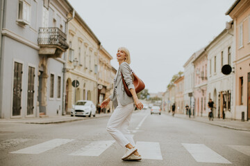 Woman walking across a crosswalk on a quiet street in the city center during the day