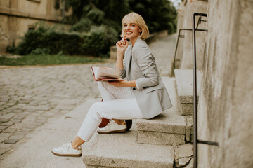 Woman enjoying a book while sitting on steps in a scenic outdoor location