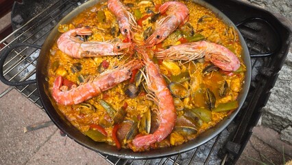Delicious spanish paella with seafood and vegetables in rustic pan setting. Typical cuisine of Spain. Valencian cuisine. Stage of cooking paella. Ingredients for paella