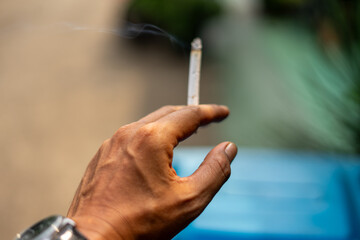 Adult Hand Holding Lit Cigarette with Rising Smoke