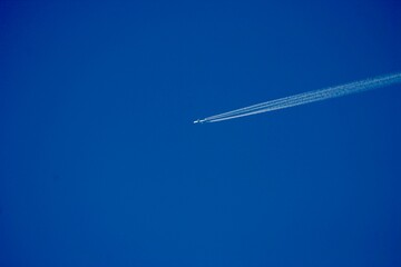 White contrails streak across a vivid blue sky, trailing high-flying jets. These icy lines slowly fade, tracing silent paths through the crisp, clear atmosphere on a calm, cloudless day.