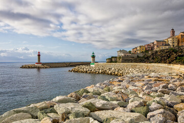 Entrance to Bastia's old harbor with its two lighthouses and view of the citadel in the warm morning sunlight