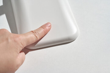 Close-up of hand touching smooth white corner object under bright light surface.
